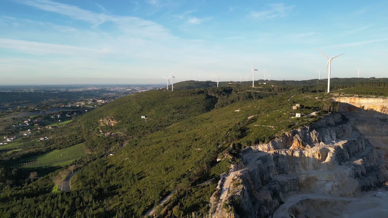Vista aerea di turbine eoliche e cava in un paesaggio verde.