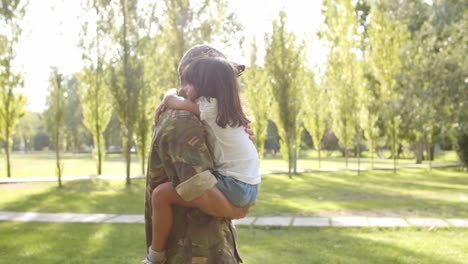 soldier dad carrying daughter in arms in the park