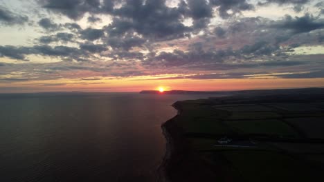 aerial 4k drone footage of lowering down along the coast on the isle of wight at a golden sunset