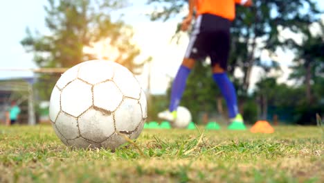 soccer ball on field on blurred soccer athletic playing and training control ball and shoot to goal on field in sunset