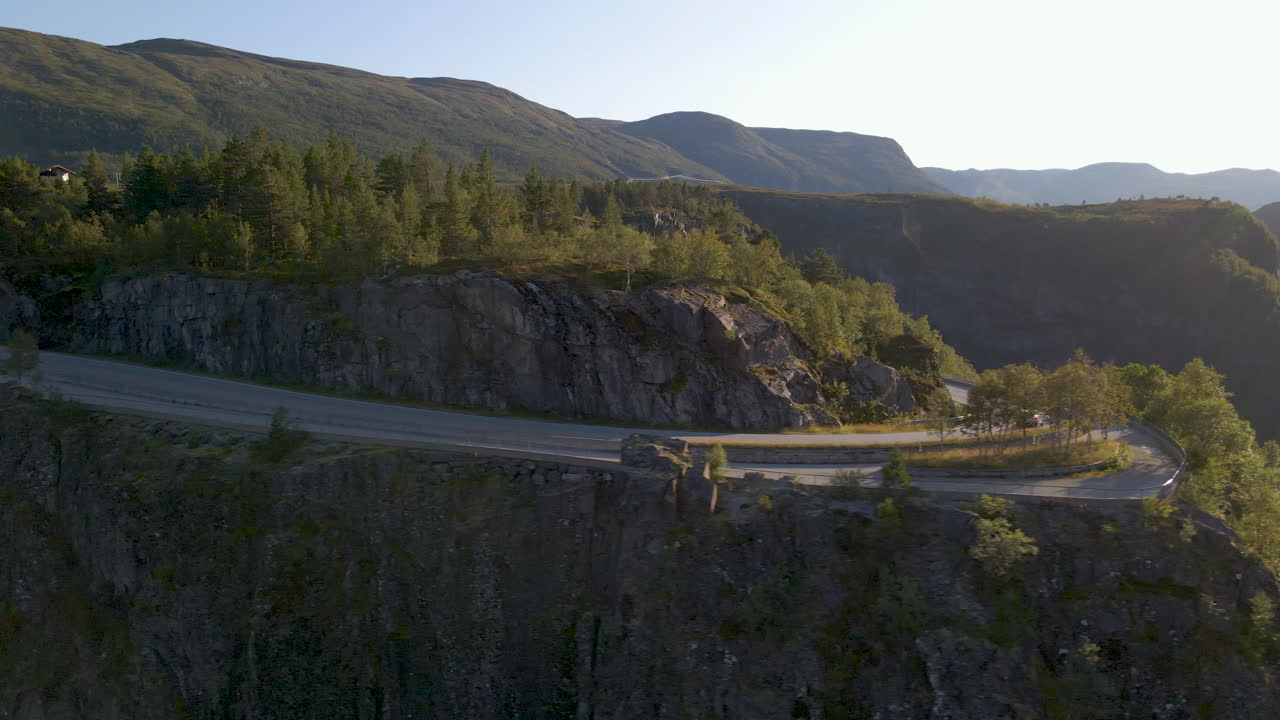 Car on winding road leading to Voring Falls on sunny summer day, Norway, aerial shot