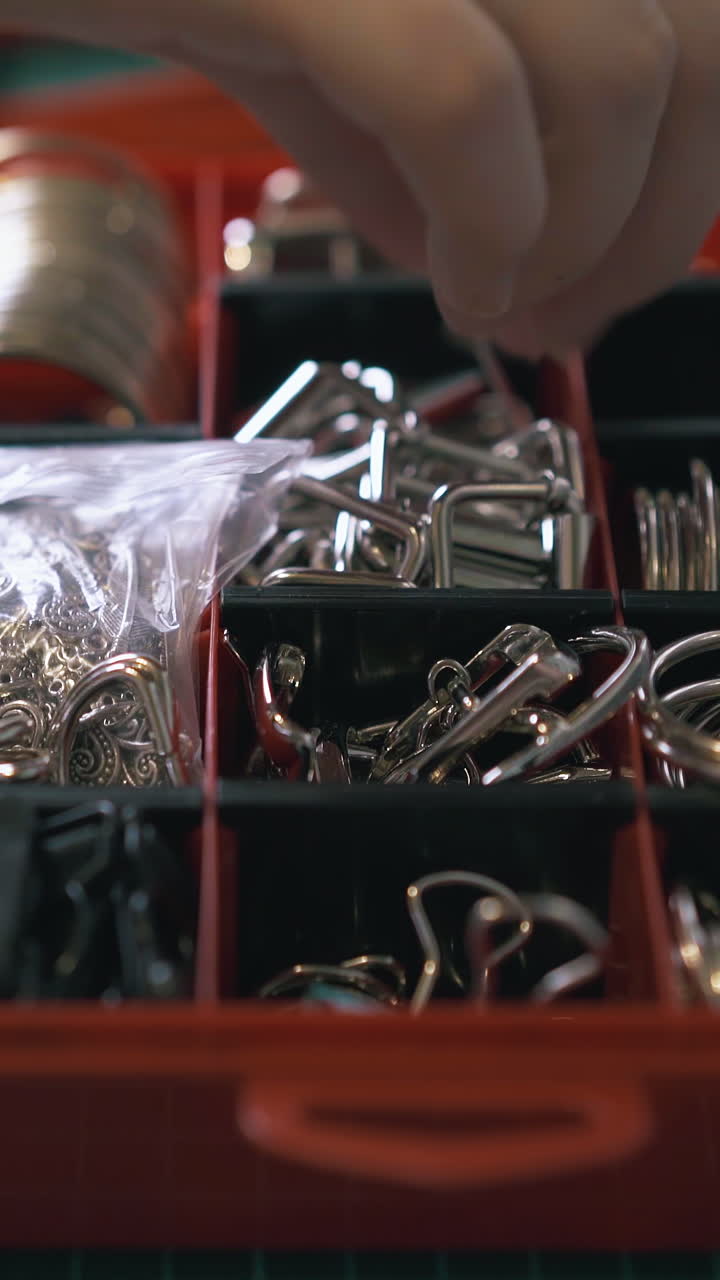 CU: Professional girl tailor hand takes accessory from red box on green cutting board in workshop close view