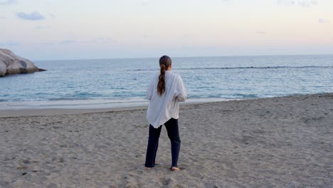 Junges-Mädchen-Tanzt-Mit-Blick-Auf-Den-Friedlichen-Strand-Bei-Sonnenuntergang,-Weitwinkelaufnahme-Von-Hinten,-Teneriffa