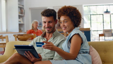 pareja en casa con una tableta digital haciendo compras o reservas con tarjeta de crédito