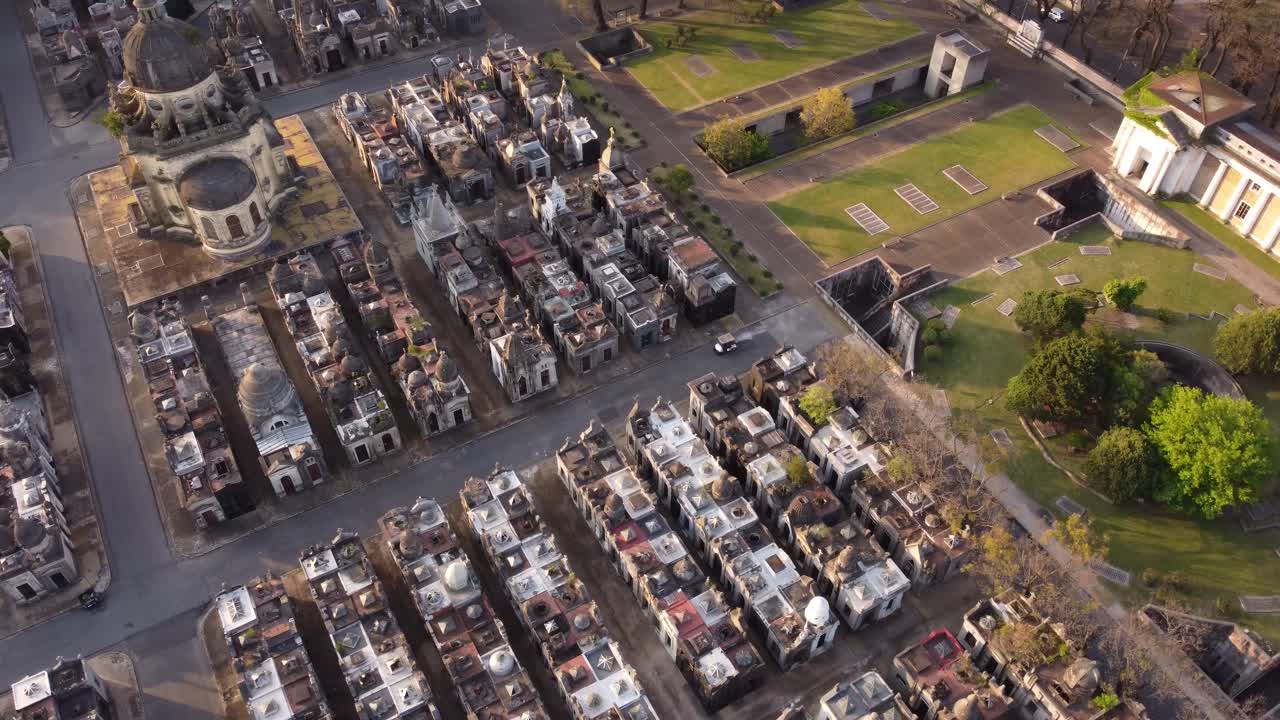 небольшой автомобиль едет по дороге на кладбище чакарита в буэнос-айресе во время солнечного света - съемка с дрона сверху вниз церкви и надгробий