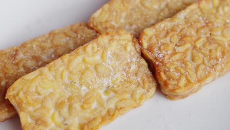 closeup shot, fingers grab fried tempeh indonesian traditional dish of fermented soy beans