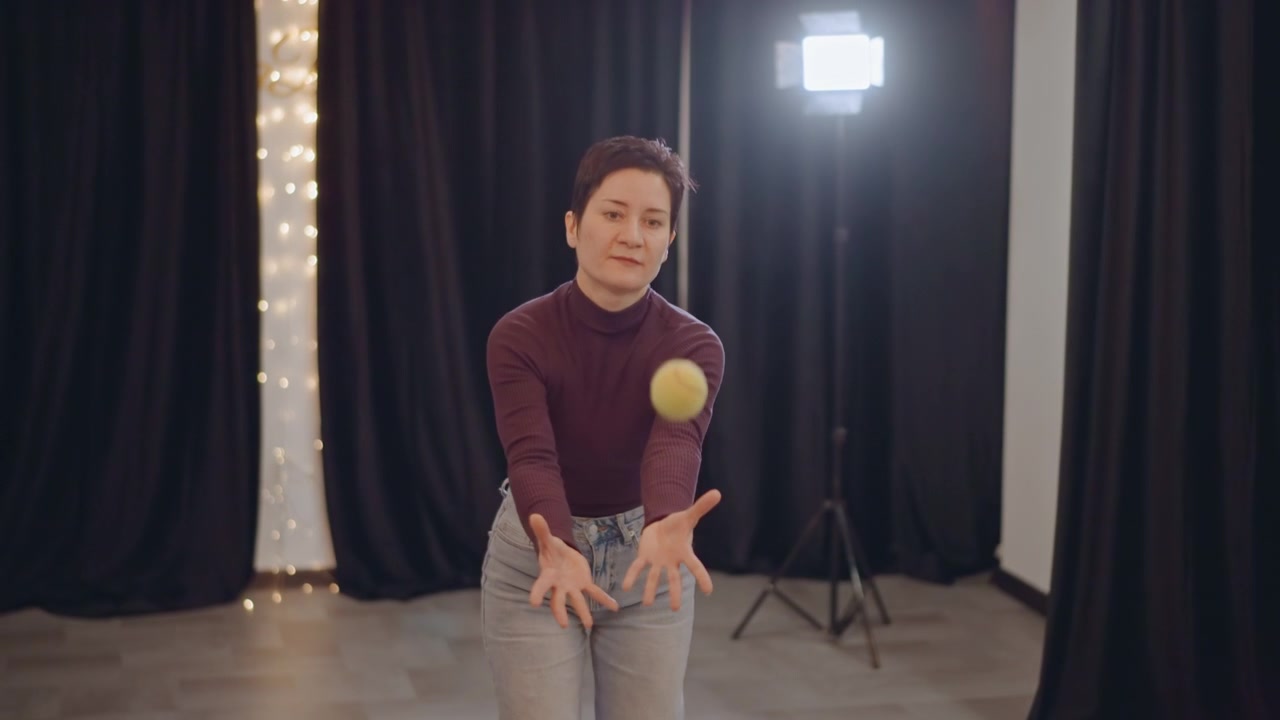 Studio floor asian movement coach practices ball rhythm and posture drills, soft box light and black curtains, solo training focused on balance and timing, deliberate slow motions and breath control