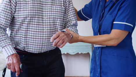 Krankenschwester-Hilft-älterem-Mann-Beim-Gehen-Mit-Einem-Gehstock,-Mittelteil