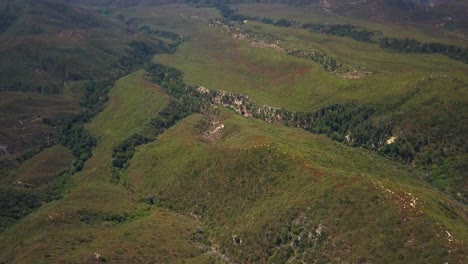 Aerial of grassy ridge and tilt up to reveal vast valley far below. 4K