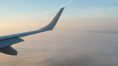 airplane wing and winglet, passenger view of plane flying above clouds