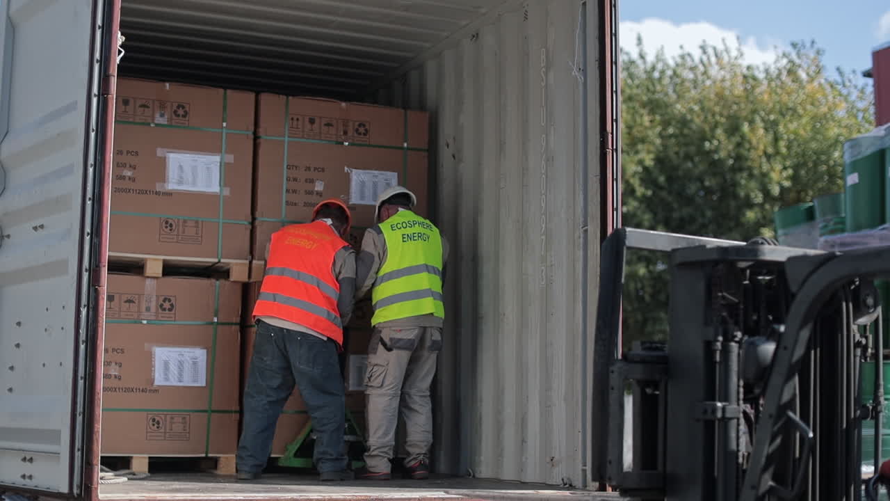 Workers Loading Cargo Containers with Forklift