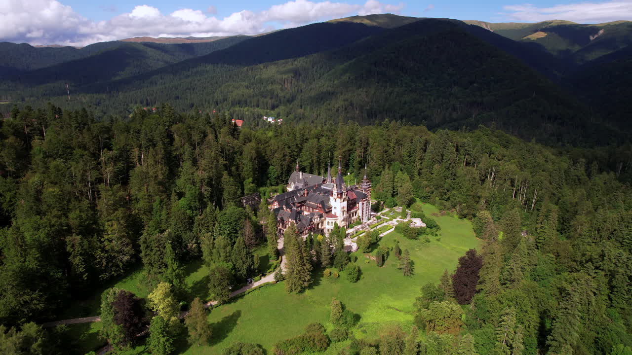 Drone flying backwards revealing castles in the forest of Sinaia