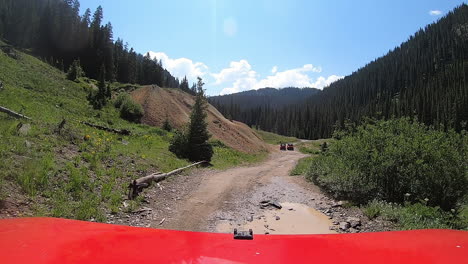 punto de vista sobre la capota roja de un vehículo 4wd en el sendero circular alpino siguiendo a otros 2 vehículos todoterreno en el valle del río animas cerca de silverton colorado en las montañas de san juan