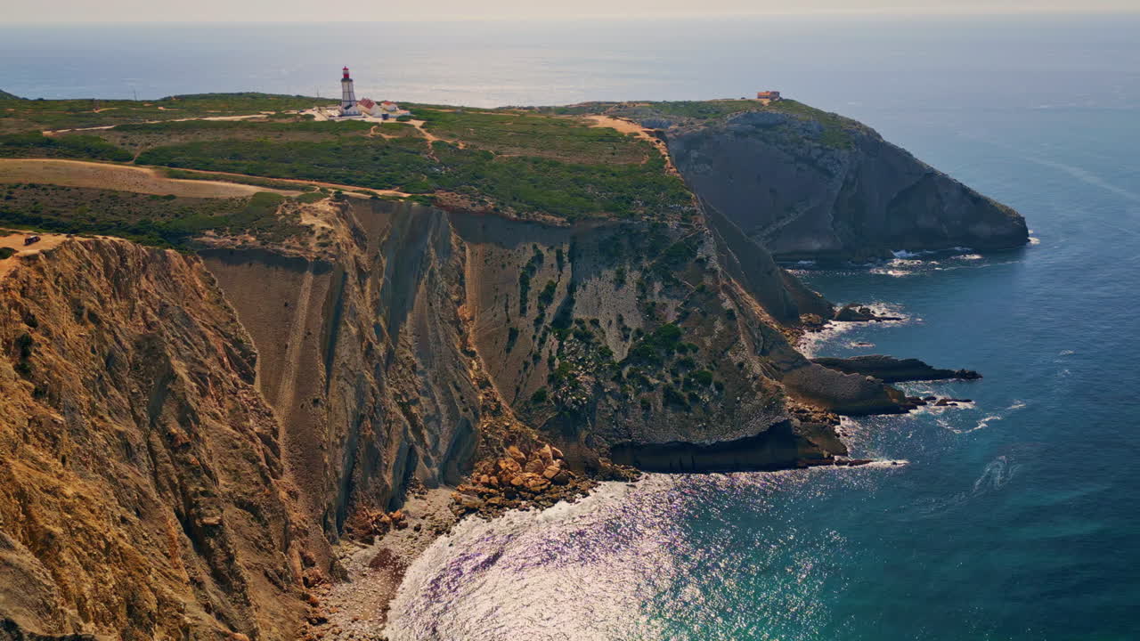 Stunning ocean cliffs summer evening aerial. Lighthouse standing on coastal rock