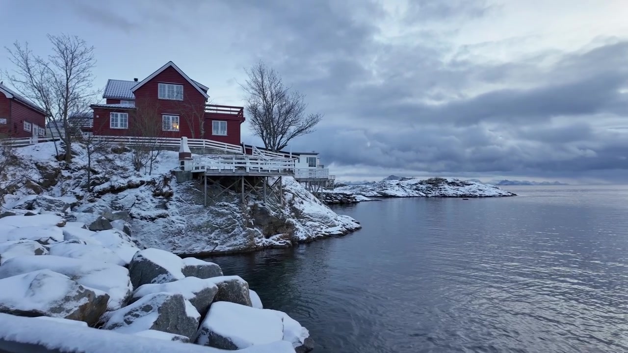 Pintoresca costa nevada con una cabaña roja en Svolvear, Noruega, ambiente tranquilo.