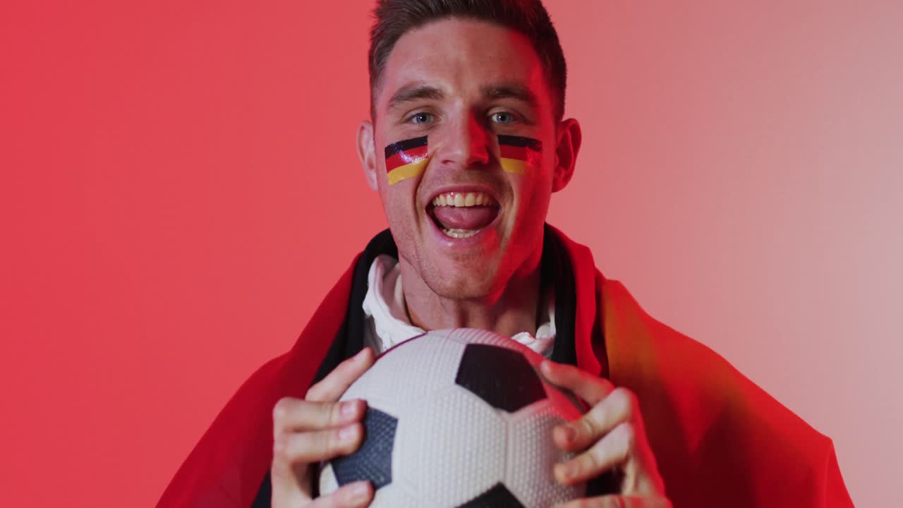 retrato de un feliz seguidor de fútbol masculino caucásico con la bandera de alemania sobre iluminación rosa