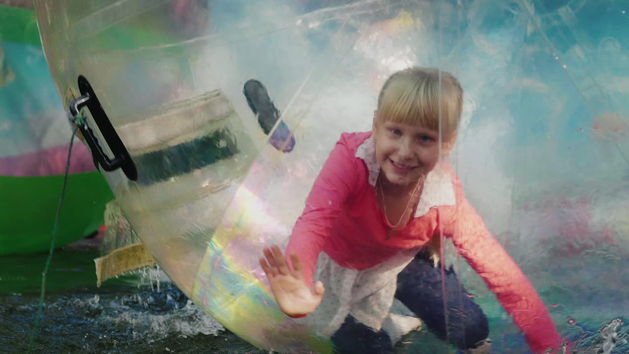 diversión en el agua una niña alegre juega dentro de una bola transparente en la piscina 4k cámara lenta v