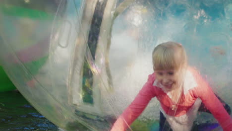 fun on the water a cheerful little girl plays inside a transparent ball in the pool 4k slow motion v