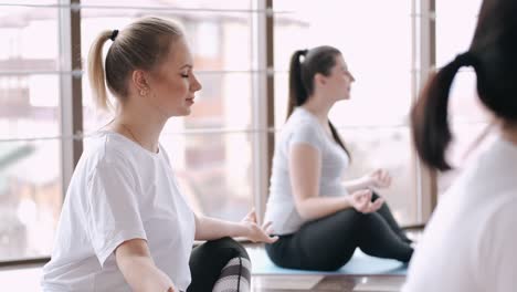 pregnant european women are doing yoga in a fitness gym