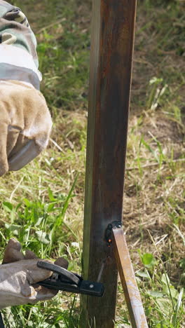 skilled craftsman uses modern welding equipment for fixing parts of country house fence in daytime