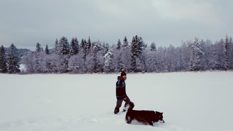 hombre caminando en la nieve fresca con el juguetón malamute de alaska durante el invierno en noruega