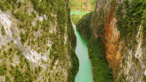 aerial dolly forward through steep canyon walls over the gorgeous turquoise blue green water of the nho que river in northern vietnam