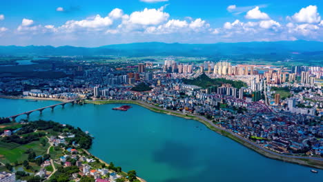 Aerial-drone-view-of-modern-city-financial-district-skyline-and-natural-scenery-with-green-river-with-bridges,-greenery,-landmark-buildings,-skyscrapers-in-the-distance