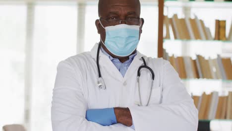 african american senior male doctor wearing white crossing his arms looking at the camera