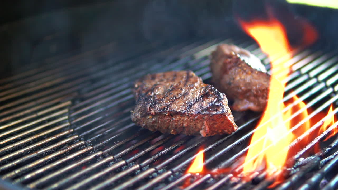 filetes a la parrilla sobre la llama abierta de una barbacoa en el patio trasero en cámara lenta