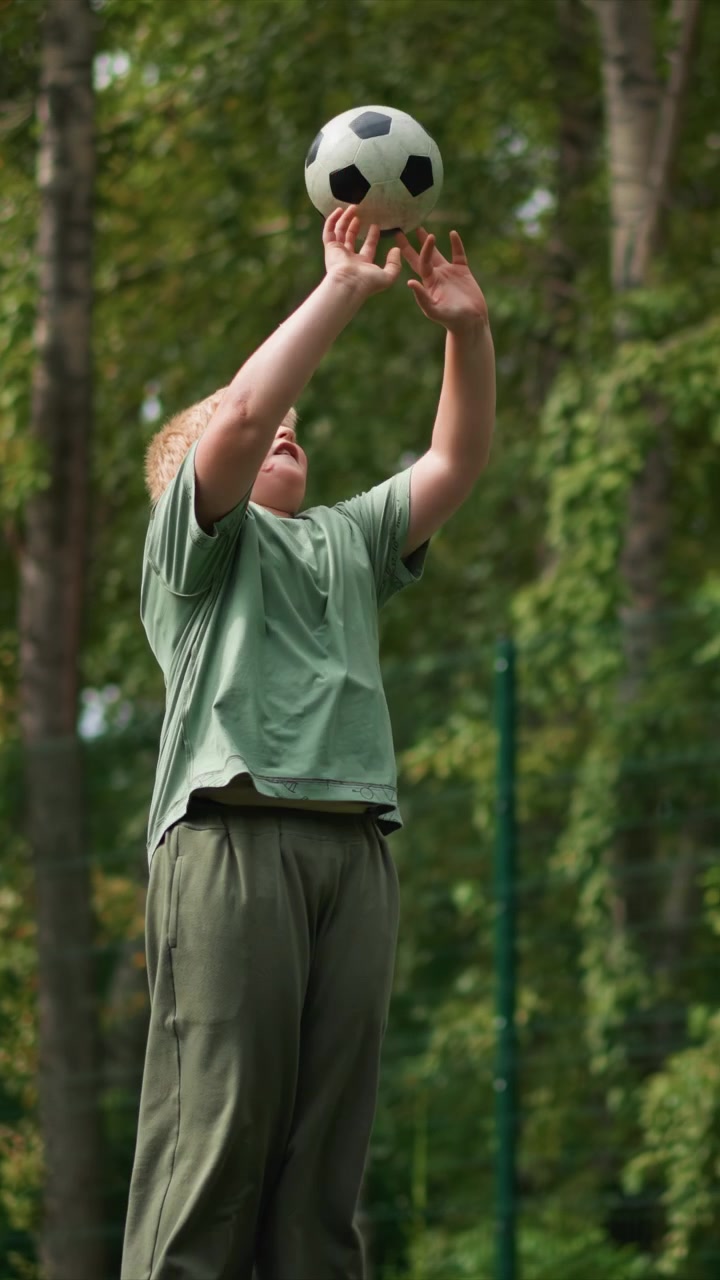 Boy with light hair wears mint green t shirt and olive pants. Object remains unseen during close up shots of legs. Green foliage serves as background for outdoor activity