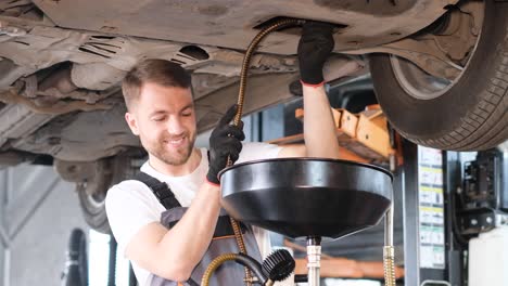 auto mechanic performing fluid drain under a car