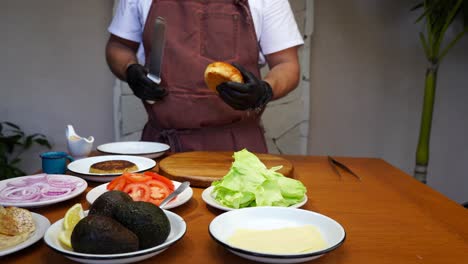 chef asador preparando una hamburguesa de pescado con ingredientes en la mesa