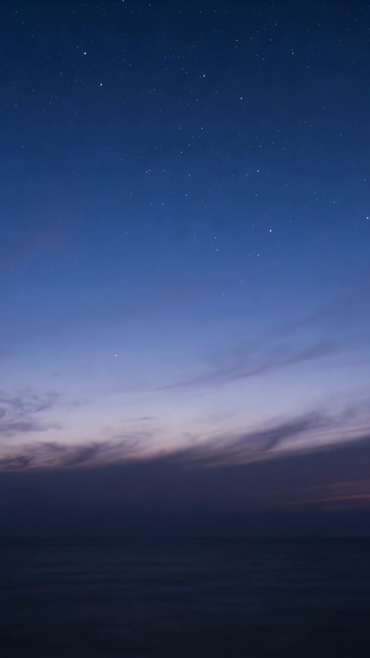 Vertical video: Deepening sky revealing stars, drifting thin clouds at coastal horizon and calm sea