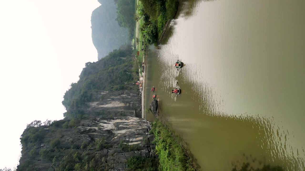 vertical aerial shot overhead tourists sailing in the Ngo Dong river to caves