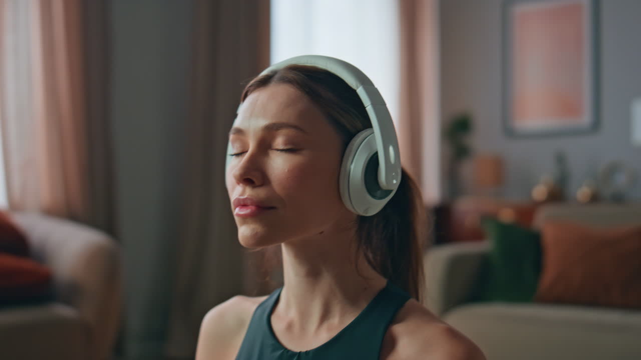 Calm lady meditating headphones at apartment closeup. Woman closing eyes at home