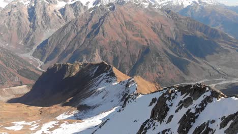 Flying-passed-a-snow-capped-mountain-peak-to-reveal-a-beautiful-mountain-range-valley-in-Georgia