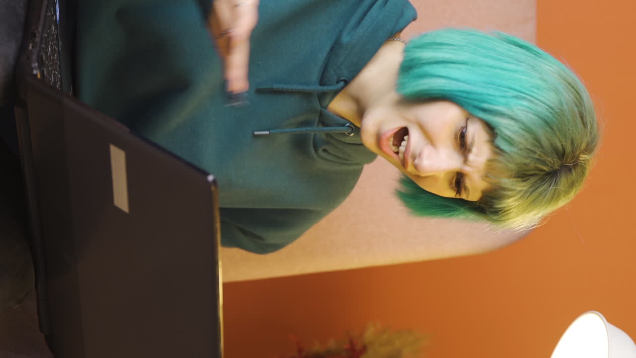 video vertical de una mujer joven cerrando una computadora portátil con una expresión de enojo.