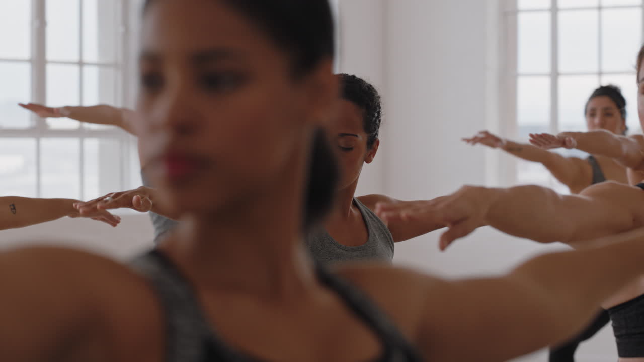 beautiful yoga woman instructor teaching reverse warrior pose meditation with group of multiracial women enjoying healthy lifestyle exercising in fitness studio