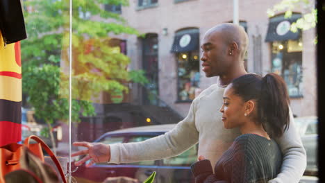 Smiling-couple-looking-in-a-clothes-shop-window,-close-up