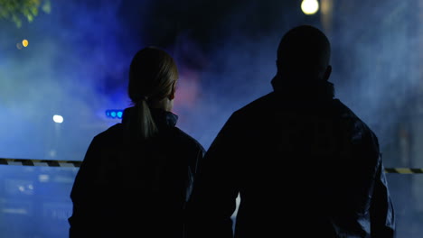 parte trasera del hombre y la mujer de razas mixtas del fbi yendo de noche a la calle a la escena del crimen