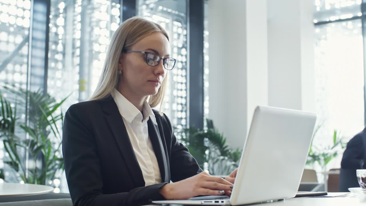 Blonde Geschäftsfrau tippt am Laptop im Coworking Space