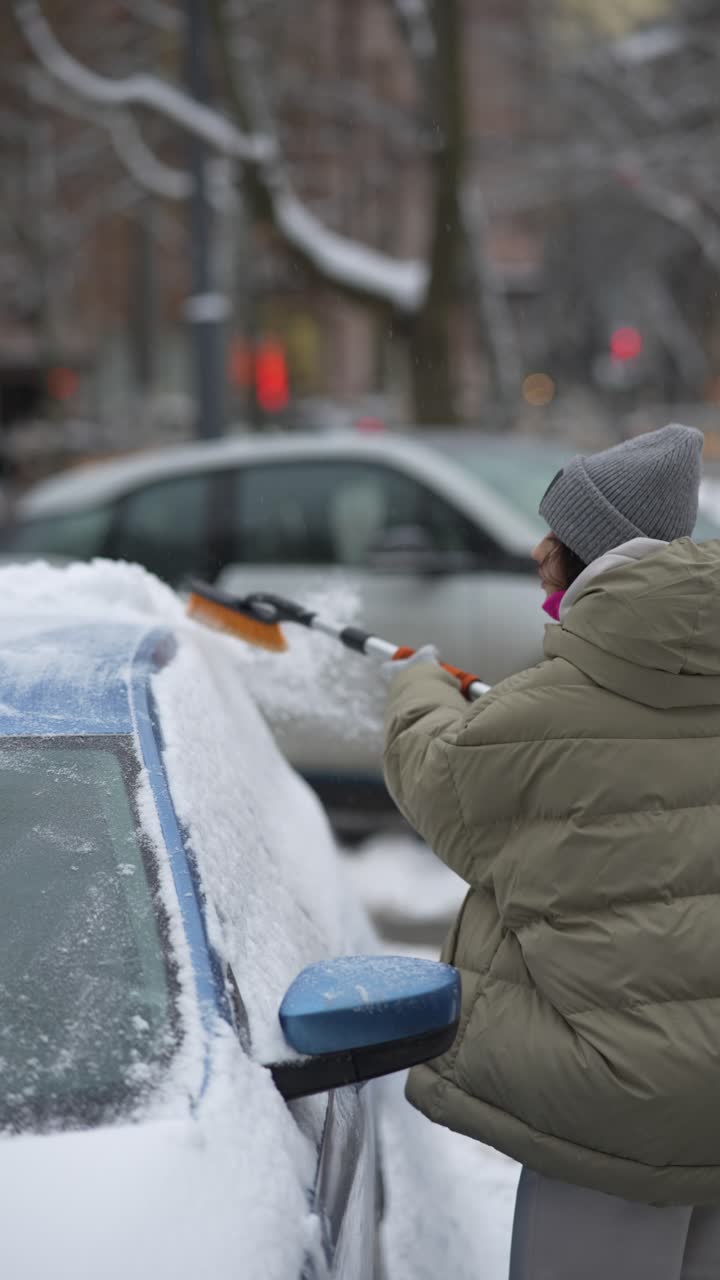 mujer quitando la nieve del coche en la ciudad nevada