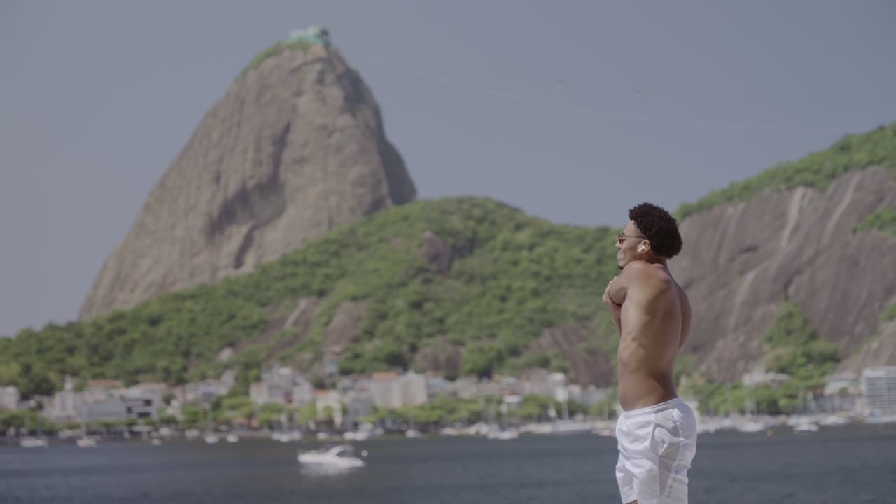 A man exercises by the water with Sugarloaf Mountain in Rio de Janeiro