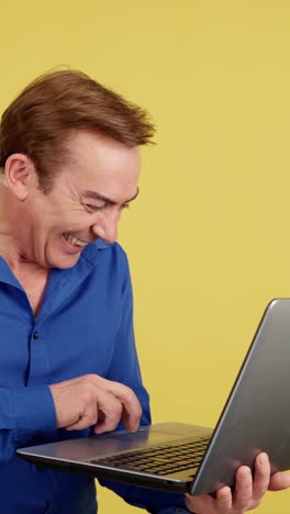 Man Laughing while Using a Laptop