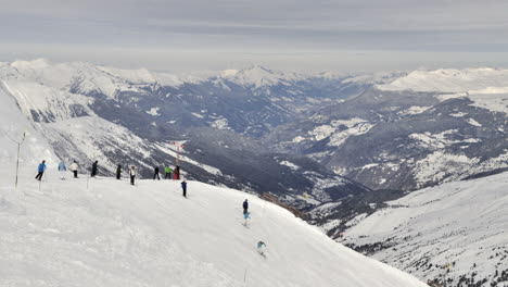 time lapse of skiers , skiing down a slope-piste in french alps with snowy valley behind