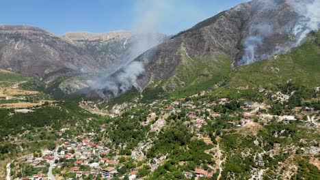 fires burning the mountain and forest closing in on the village at the foot of the mountain emitting smoke and ash