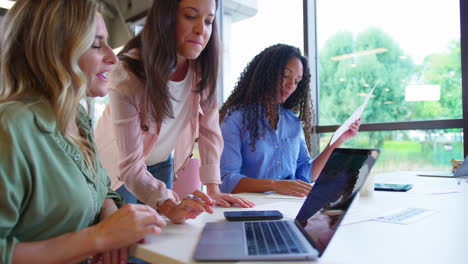 Equipo-De-Negocios-Femenino-Multicultural-Sentado-En-El-Escritorio-Con-Una-Computadora-Portátil-En-La-Oficina-Colaborando-En-El-Proyecto