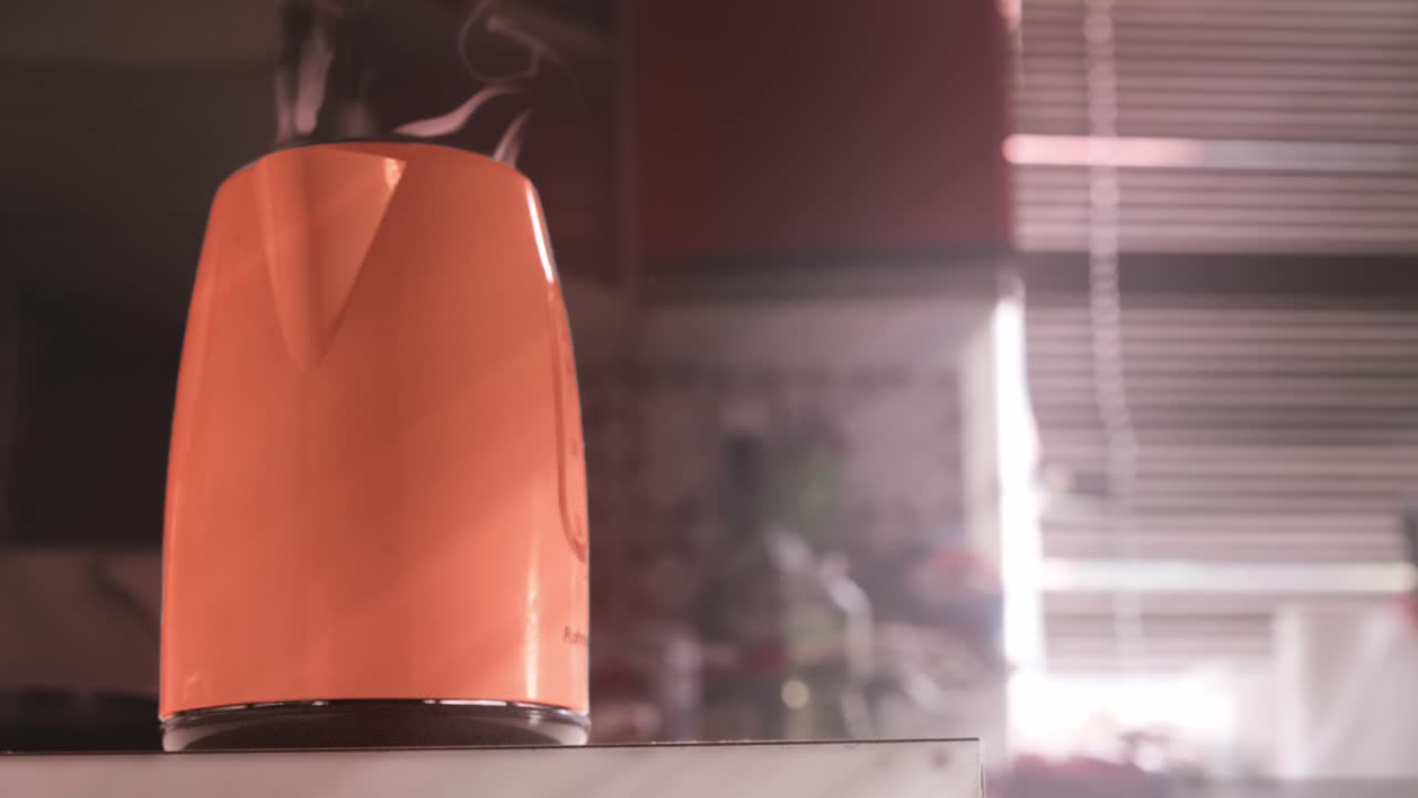 De la vapeur chaude s’échappe d’une cafetière orange dans une cuisine chaleureuse et accueillante avec espace de copie