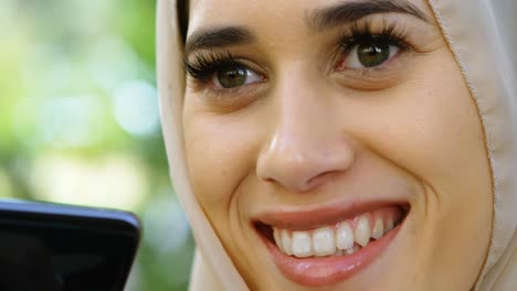 Woman-in-hijab-smiling-while-using-mobile-phone-4k