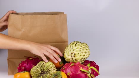 hands placing fruits into a paper bag